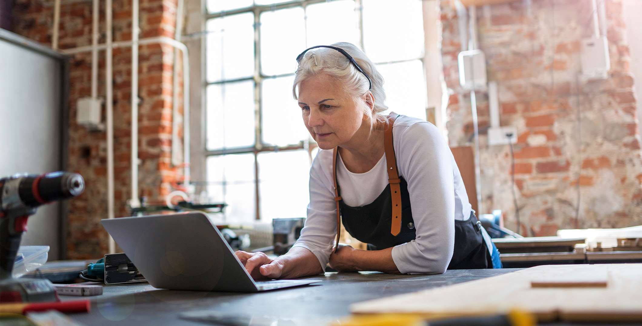 Older lady working with laptop and various tools