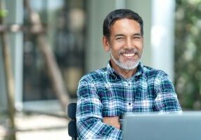 Portrait of happy mature man with white, grey stylish short beard looking at camera outdoor. Casual lifestyle of retired hispanic people or adult asian man smile with confident at coffee shop cafe.