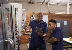 Engineer Training Young Male Apprentice On CNC Machine